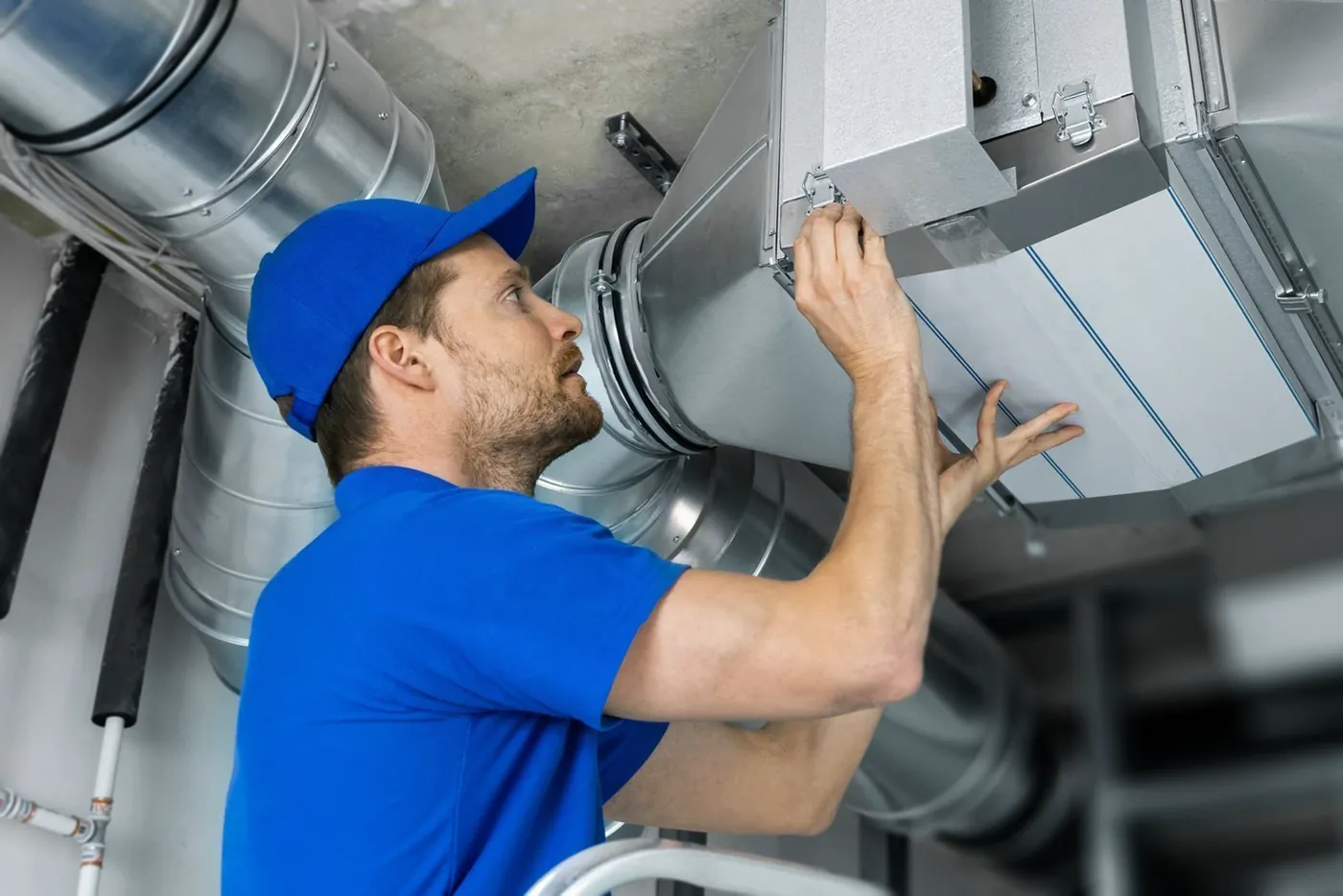 Technician inspecting overhead ductwork for a ventilation system